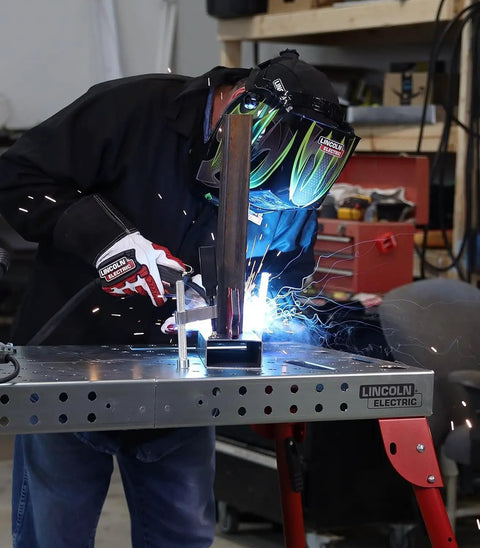 Person welding on Heavy Hitter Portable Welding Table Folding Workbench 21 X 44 Inches Flat Steel Surface Clamping Grid.