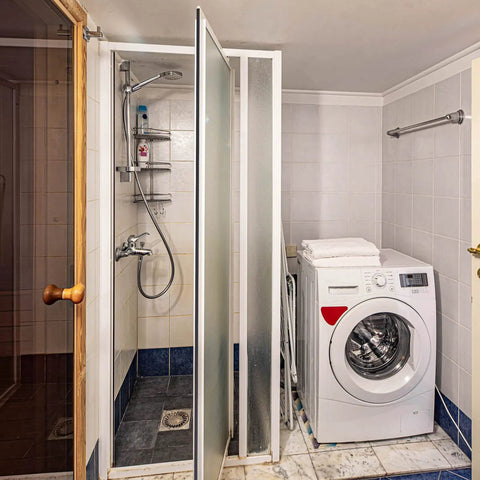 Bathroom scene with shower setup next to a washing machine, no visible 75 Inch Flexible Magnetic Shower Door Seal Strip For Framed And Semi Framed Glass Doors Replacement Magnetic Strip Easy Cut Black Roll Must Have For Swinging Shower Doors.