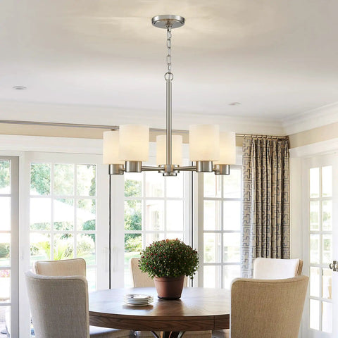 Dining room with round table and brushed nickel chandelier overhead, modern decor.
