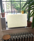 Legit Indoor Window Ac Cover That Keeps Your Setup Sharp And Shields Five To Seven Thousand Btu Units Fitting 21 By 15 By 3.5 Inches From Brisk Weather And Dust Builds Using Soft Washable Polyester In Crisp White on window unit with plants.