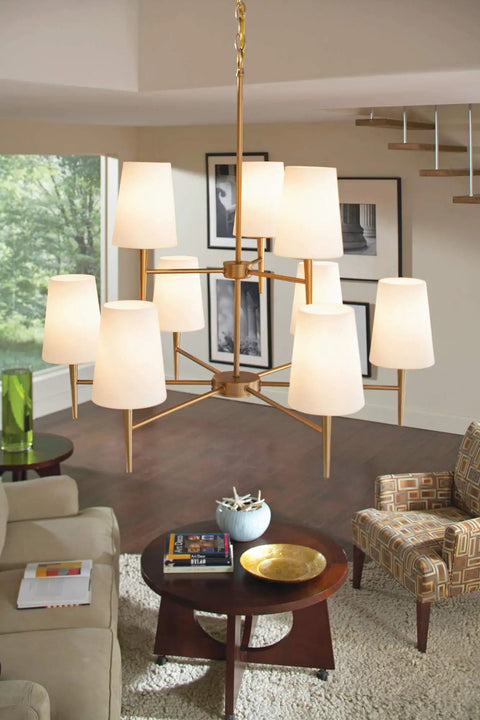 Modern living room with large gold chandelier and warm lighting over a wood coffee table and patterned armchairs