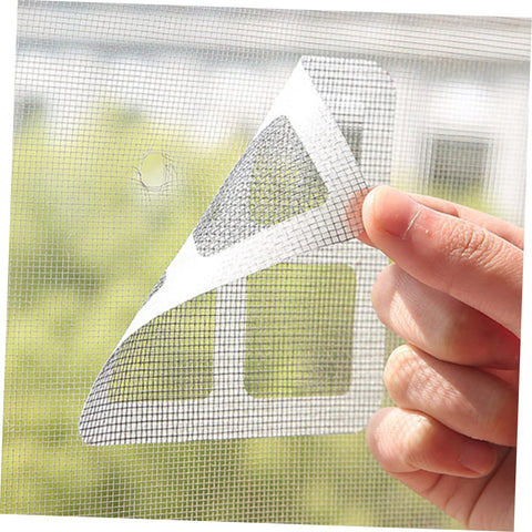 Hand applying DIY Window And Door Screen Patch Kit With 20 Fiberglass Mesh Patches for quick fixes of holes in window screens.