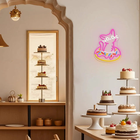 Cat-shaped neon sign and cake display in a cozy café setting