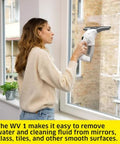 Side view of white Kärcher WV 1 10-inch electric window vacuum squeegee used on a glass window.