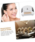 Woman smiling while wearing earrings next to Solar Powered Rotating Display Turntable For Jewelry Phones And Accessories.