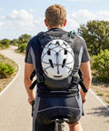 Cyclist wearing Lightweight Running Vest With 2L Water Bladder, helmet attached, on a sunny road.