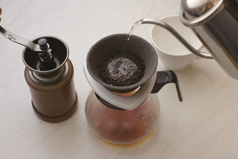 Japanese Ceramic Coffee Filter With Reusable Blue Dripper Stand And Eco Friendly Micropore Design For A Smooth Next Level Pour Over Brew That Truly Hits Different with water being poured over coffee grounds.