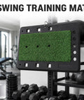 Pro-Grade Swing Training Mat For Golf Practice Rubber Hitting Pad hanging in a gym with equipment around, slip-proof rubber surface