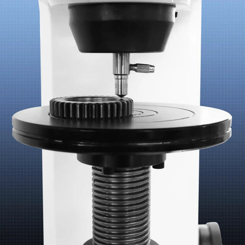 Rock Solid Digital Rockwell Hardness Tester With Four Inch Color Touch Screen and Motorized Build measuring gear on black platform.