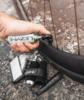 Twin Speed CO2 Inflator Bike Repair Kit with lever used on flat tire next to bike wheel with cartridges and tools