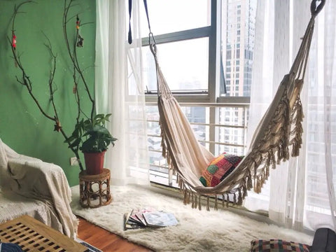 Handmade Boho Macrame Fringe Double Hammock Swing Net Chair For Two People Ultra Cozy Outdoor Indoor Patio Beach Yard Decor 95 Inches By 59 Inches Heavy Cotton Blend For Extra Comfort And Durability in a cozy room setting with sunlight streaming through windows.