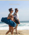 People carrying Foldable Hammock Style Camp Chair With Detachable Footrest And Padded Headrest And Seat for beach camping on sand.