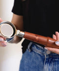 Person holding Hella Smooth Breville Espresso Accessories Kit With Bottomless Portafilter Plus Spring Loaded Tamper with rosewood handle.