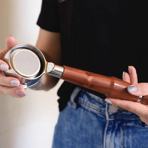 Person holding Hella Smooth Breville Espresso Accessories Kit With Bottomless Portafilter Plus Spring Loaded Tamper with rosewood handle.