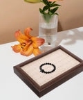 Solid Wood Earring Organizer And Ring Keeper Tray With Thirty Open Slots For Stashing Bracelets And Chains In A Rich Walnut Finish displaying a black bracelet.