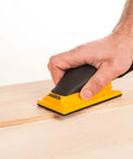 Hand using Ergonomic Pro Grade 2.75 by 5 Inch Dust Free Hand Sanding Block With 13 Hole Hook And Loop System on wood surface.