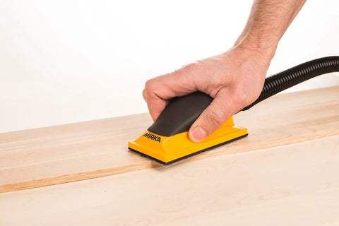 Hand using Ergonomic Pro Grade 2.75 by 5 Inch Dust Free Hand Sanding Block With 13 Hole Hook And Loop System on wood surface.