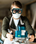 Woman wearing Kickass Dual Flip Up Welding Goggles Built Tough As Nails With Impact Resistance, using equipment in workshop.