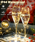 Two champagne glasses decorated with 4 Pack 60 LED Battery Operated Fairy Lights With Timer, 20 Ft Waterproof Indoor Outdoor.