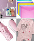 Clear tote bag with toiletries, colorful document holders, pink umbrella with sneakers, and pink baby onesie with text.
