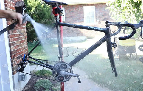 Person using a hose to clean a bike with a Bike Chain Keeper Holder For Cleaning And Lubing Wheel Dropout Chain Tensioner Tool installed.