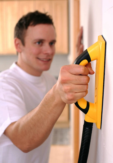 Person using Pro Grade Dust Free Hand Sanding Block Kit 3 In X 9 In with hook and loop backing and vacuum hose on a wall