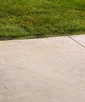 Kick Your Backyard Up A Notch With This Top Shelf Clear Satin Stamped Concrete Sealer applied on patio next to green grass.