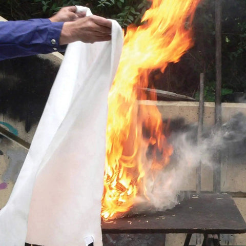 Person using Heavy Duty Fiberglass Fire Blanket 3.9 By 5.9 Feet For Emergency Survival And Kitchen Fire Safety on outdoor fire.