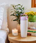 Premium Portable Breast Milk Cooler Built To Keep Pumped Storage Ice Cold For Up To 24 Hours on a wooden table with plants and candle.