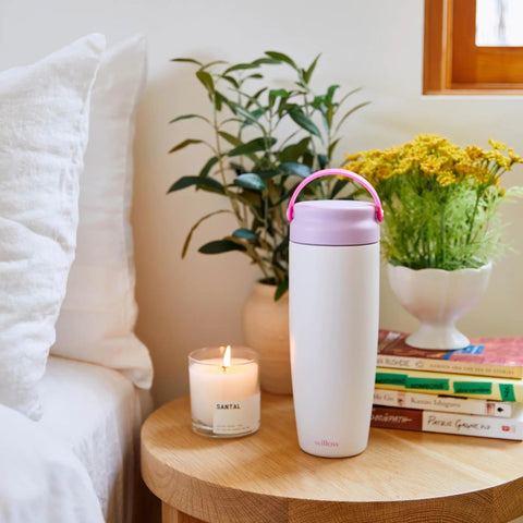 Premium Portable Breast Milk Cooler Built To Keep Pumped Storage Ice Cold For Up To 24 Hours on a wooden table with plants and candle.