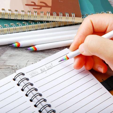 Hand writing in notebook with Rainbow Paper Pencils Set 24 Pieces Number 2 HB Graphite Pencils With White Barrels
