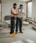 Two men in a construction site wearing Rugged Leather Steel Toe Work Boots For Men, Oil And Slip Resistant, Size US 10.5W, holding plans.