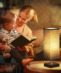 Modern Wood Table Lamp for Bedroom and Nightstand with Square Fabric Shade next to a mother reading to child on sofa