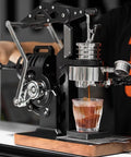 Hand Cranked Espresso Maker Boasting A 58mm Pro Brew Group And Adjustable Pressure Levers, brewing espresso into a glass.