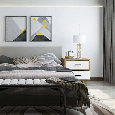 Modern bedroom with abstract art, white lamp, and wooden nightstand beside a grey bed, featuring geometric decor elements.
