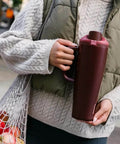 Person holding FreeSip Insulated Stainless Steel Tumbler With Built In Straw 40oz Side Handle Leak Proof in Black Cherry