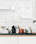 Medium Size Nail Free Wall Pegboard Organizer With Heavy Duty Hooks And Solid Wood Panel shown above a cluttered kitchen counter.