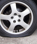 Heavy Duty 21 Piece Steel Wheel Lug Nuts With Anti Theft Hex Design on silver alloy wheel with flat tire.
