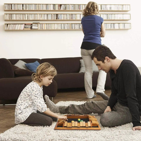 Family playing Shut The Box Dice Game on a solid wood tabletop, ideal for 1 to 4 players, in a cozy living room setting.
