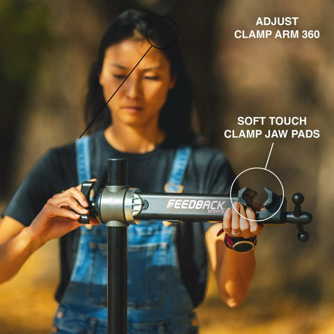 Person adjusting pro grade bike repair stand with 360 degree clamp and spinner knob for precise closure, focus on clamp and pads.