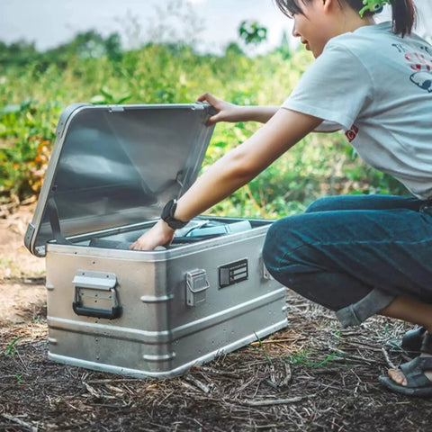 Rugged Folding Storage Box With Lid Heavy Duty Aluminum Frame Stackable Gear Crate Built Tough For Camping And Picnics, hands opening lid.