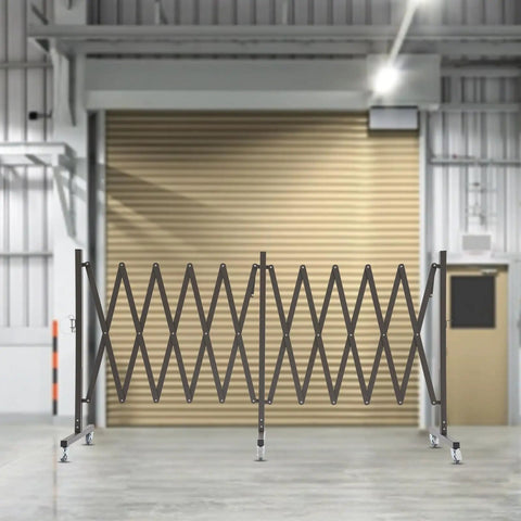 Straight Up Heavy Duty Expandable Metal Barrier On Wheels, Adjustable Retractable Safety Fence For Crowd Control, Rolling Traffic Gate With Locking Casters, Foldable Industrial Yard Barrier, Coffee Brown, shown in a warehouse.