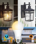 Image showing Dusk To Dawn Outdoor Sensor Light Bulbs No Fuss Auto On Off 11W LED 100W Equivalent Warm White 3000K 4 Pack 1200 Lumens E26 Base Photocell Porch Garage Security Lights illuminating a porch lantern at night and off during day below a modern house.