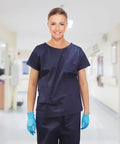 Model wearing Pack Of Ten Dark Blue Disposable Scrub Shirts Unisex Adult Large Lightweight Spunbond Polypropylene.