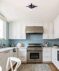 Modern kitchen with Black Star Flush Mount Ceiling Light With Dope Mid Century Vibe, white cabinets, and stainless steel appliances.
