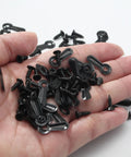 Close-up of black metal picture frame turn-button fasteners and screws (100-pack) in hand