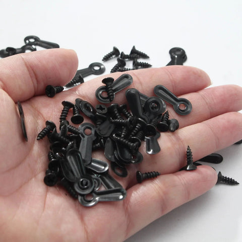 Close-up of black metal picture frame turn-button fasteners and screws (100-pack) in hand