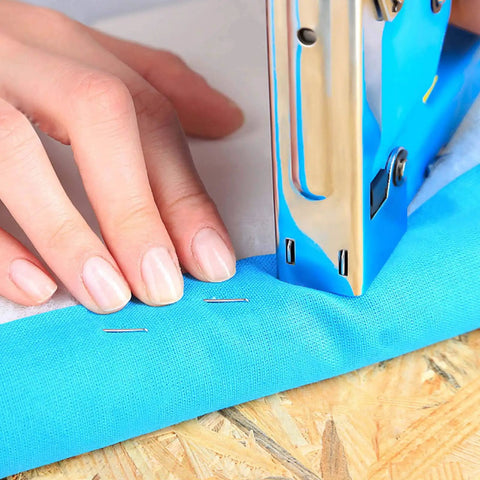 Light Duty Stapler Kit With 1600 Pc JT21 Staples Five Sixteenth And Three Eighth Inch All Steel Tacker being used on blue fabric on wood surface