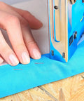 Close-up of 3 In 1 Heavy Duty Staple Gun Set With Remover All Steel Construction 2000 Staples being used on blue fabric