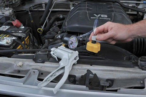 Radiator And Cooling System Pressure Test Kit for Asian, European, and US cars under vehicle hood in use.